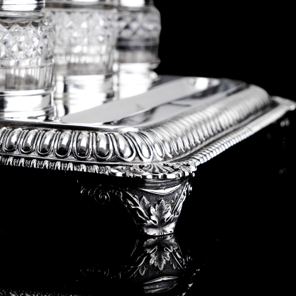 A rectangular Regency sterling silver inkstand featuring gadrooned borders, shell corners, two pen depressions, and three cut glass pots with silver lids. View XI