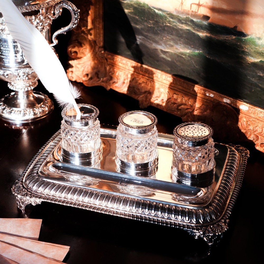 A rectangular Regency sterling silver inkstand featuring gadrooned borders, shell corners, two pen depressions, and three cut glass pots with silver lids. View XIV