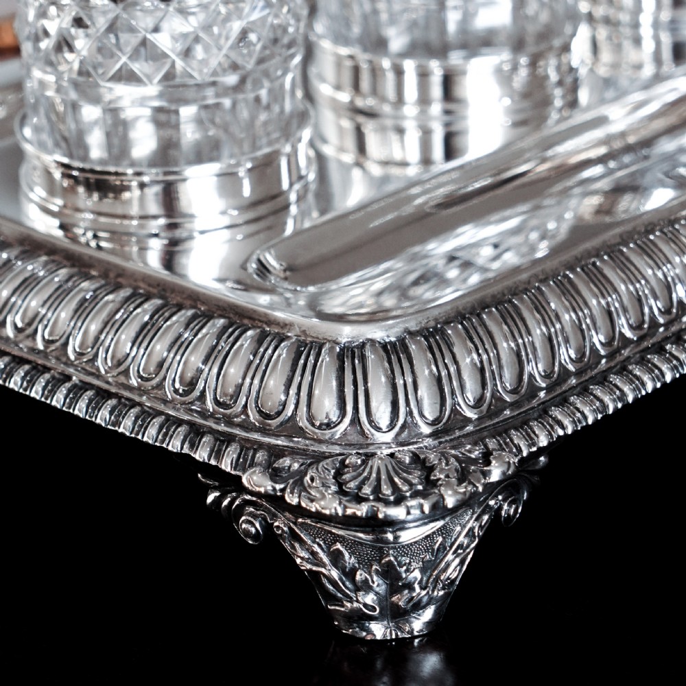 A rectangular Regency sterling silver inkstand featuring gadrooned borders, shell corners, two pen depressions, and three cut glass pots with silver lids. View XVIII