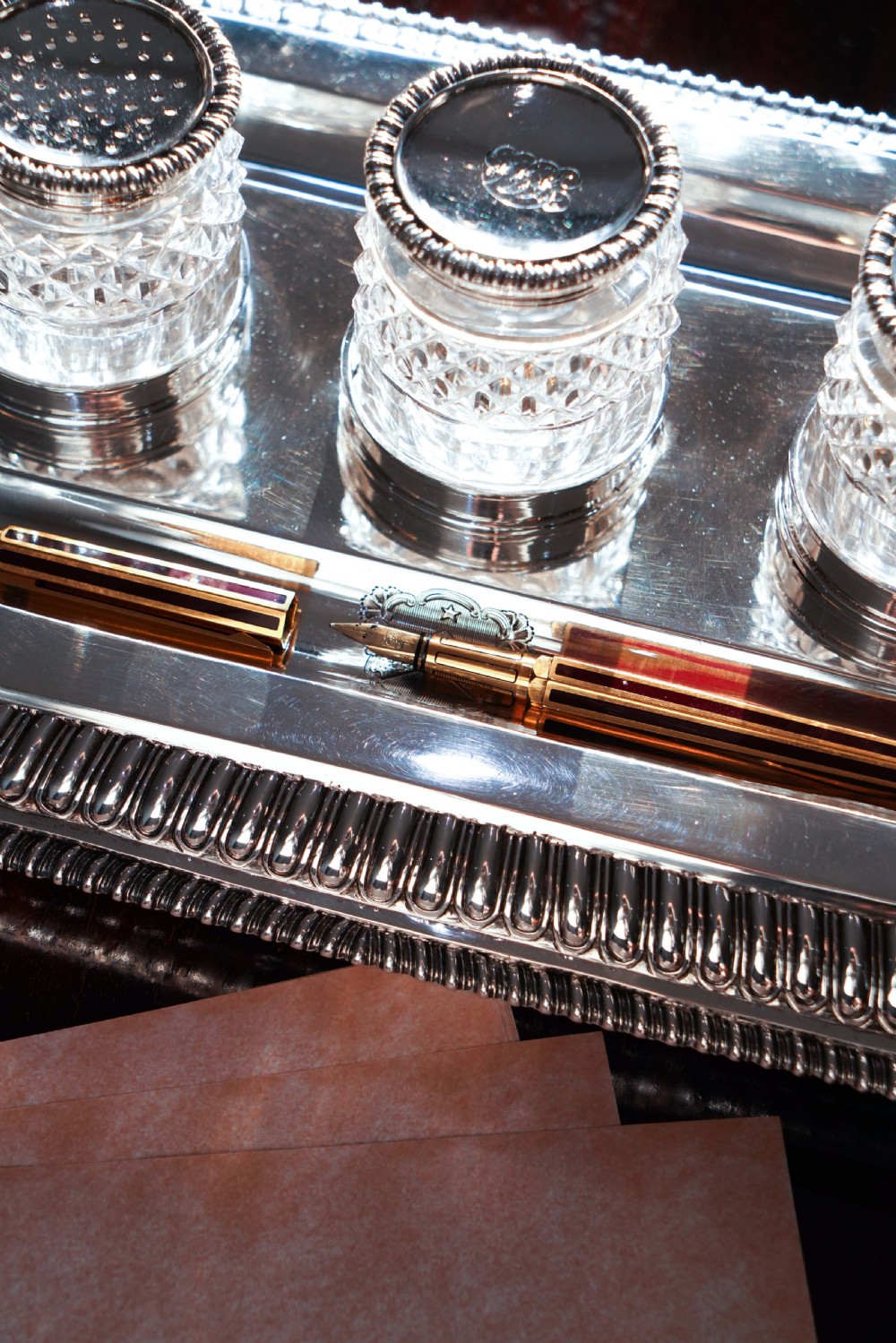 A rectangular Regency sterling silver inkstand featuring gadrooned borders, shell corners, two pen depressions, and three cut glass pots with silver lids. View XXI