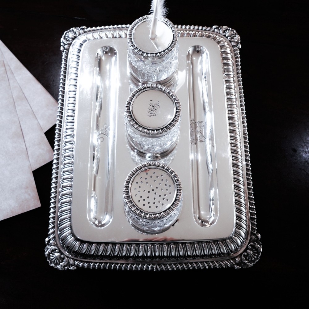 A rectangular Regency sterling silver inkstand featuring gadrooned borders, shell corners, two pen depressions, and three cut glass pots with silver lids. View XXIII