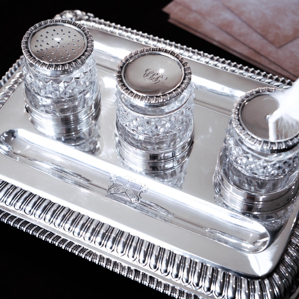 A rectangular Regency sterling silver inkstand featuring gadrooned borders, shell corners, two pen depressions, and three cut glass pots with silver lids. View XXV