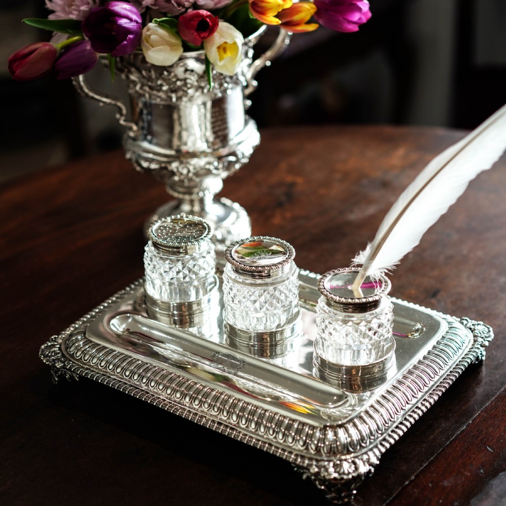 A rectangular Regency sterling silver inkstand featuring gadrooned borders, shell corners, two pen depressions, and three cut glass pots with silver lids. View XXIX