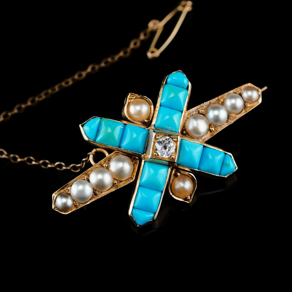 An antique Victorian gold cross-shaped brooch set with cabochon turquoise, white seed pearls, a central diamond, and attached to a safety chain. View VIII