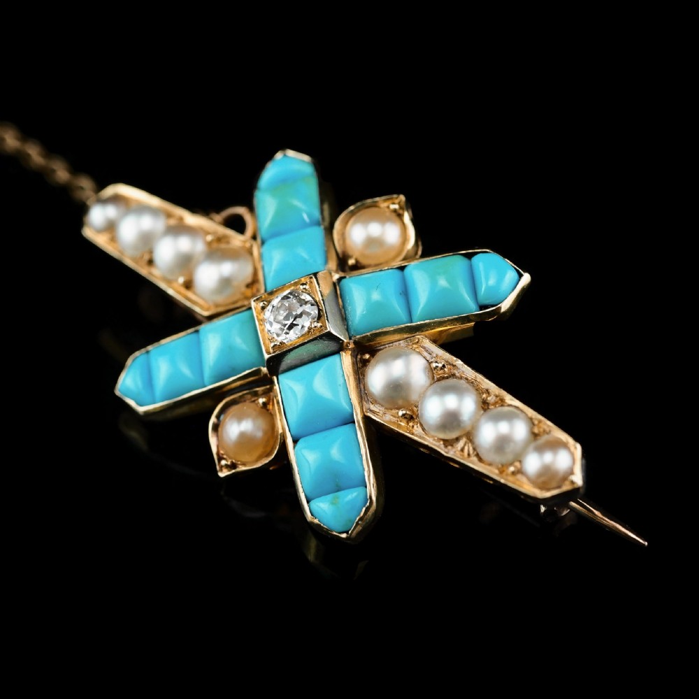 An antique Victorian gold cross-shaped brooch set with cabochon turquoise, white seed pearls, a central diamond, and attached to a safety chain. View XI
