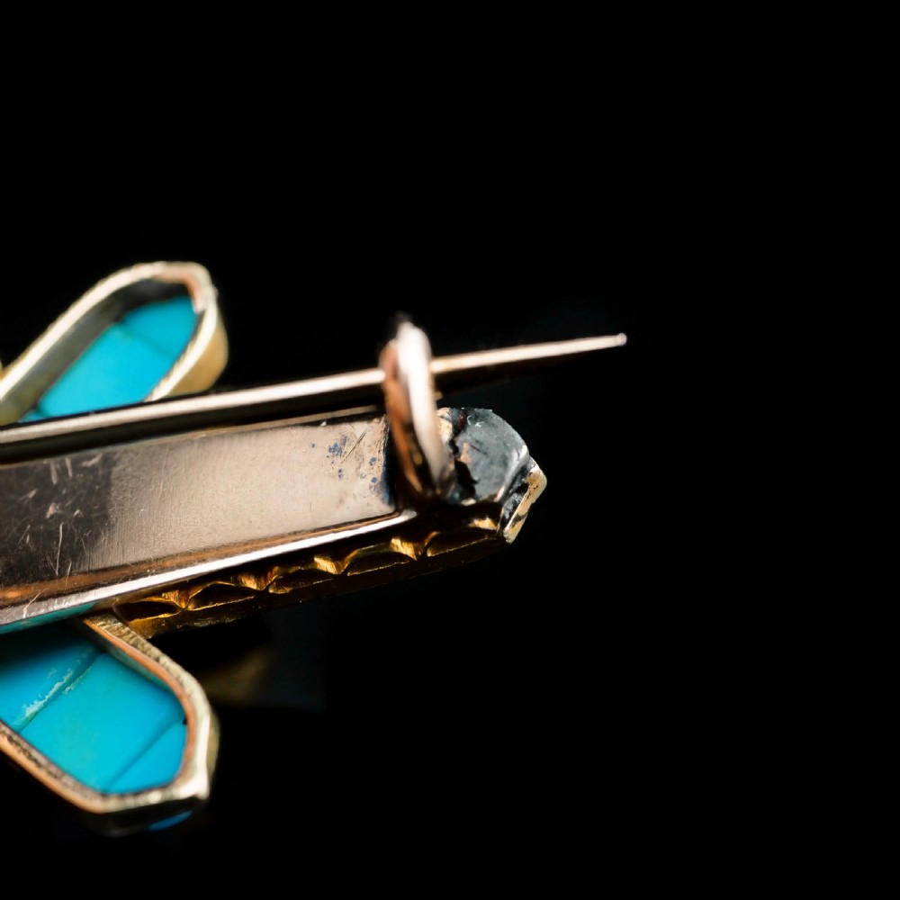 An antique Victorian gold cross-shaped brooch set with cabochon turquoise, white seed pearls, a central diamond, and attached to a safety chain. View XII
