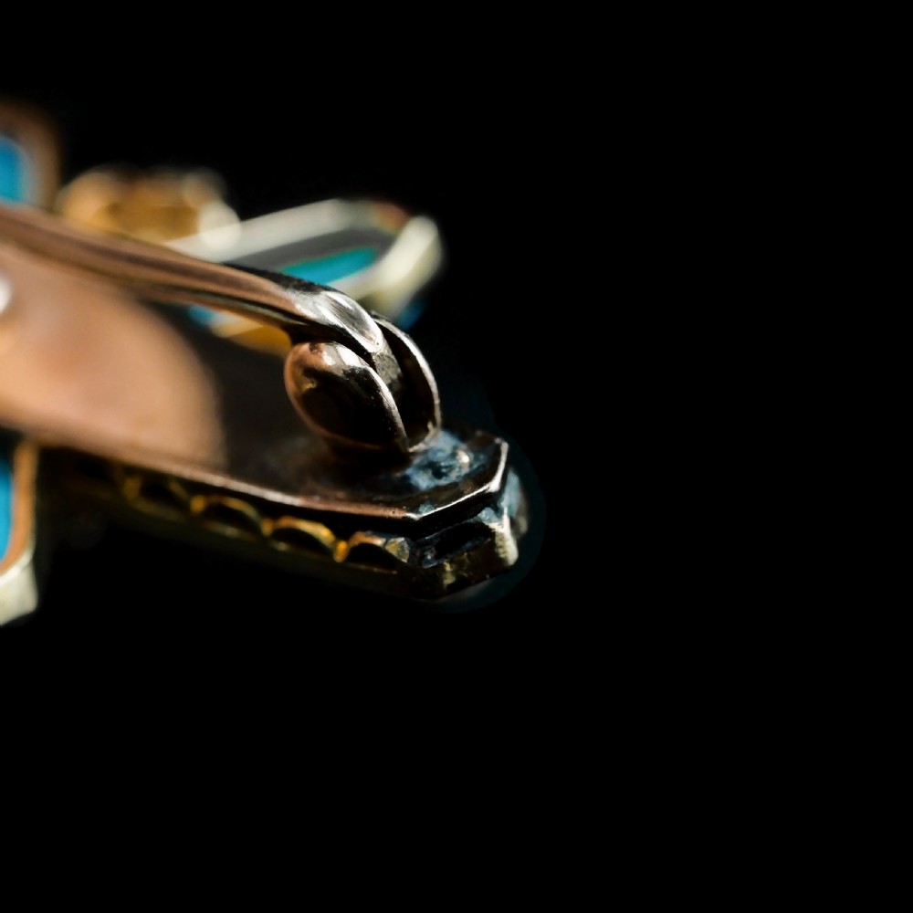 An antique Victorian gold cross-shaped brooch set with cabochon turquoise, white seed pearls, a central diamond, and attached to a safety chain. View XIII