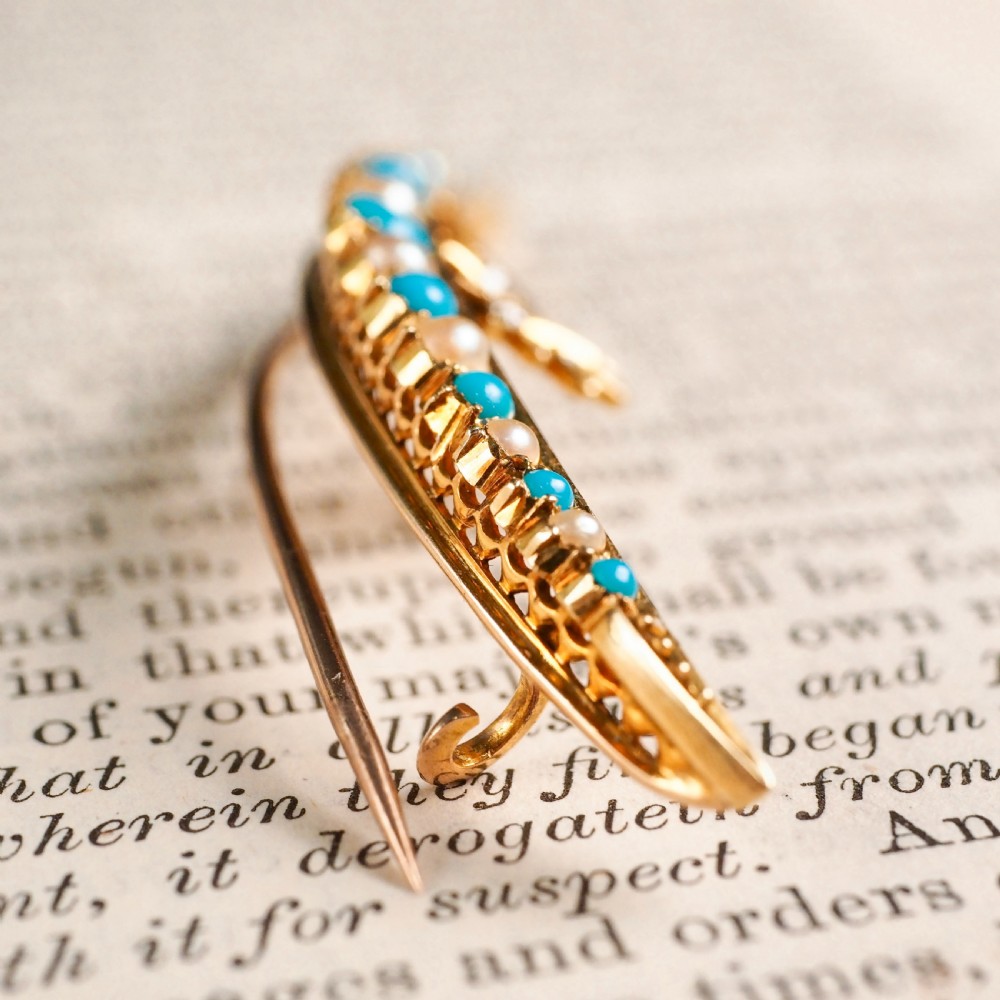 A Victorian 15ct yellow gold crescent brooch set with alternating turquoise cabochons and split pearls, featuring an offset diamond trefoil motif. View VI