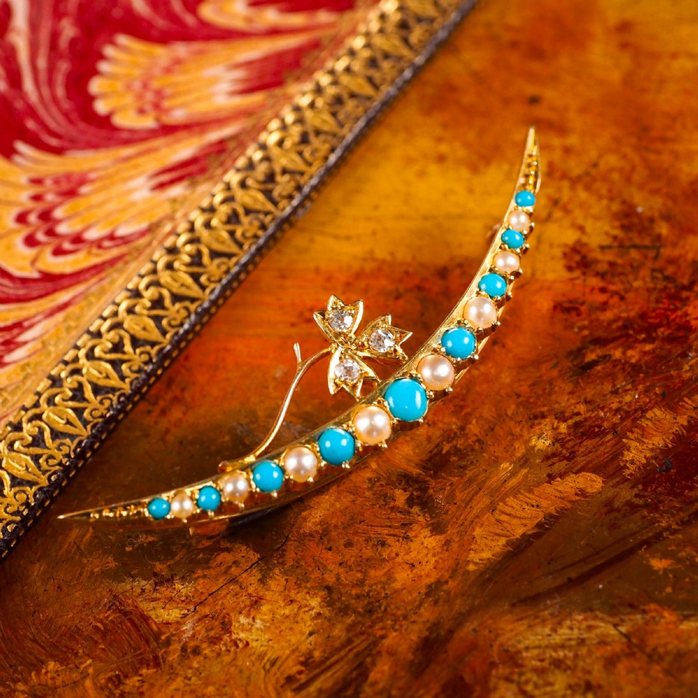A Victorian 15ct yellow gold crescent brooch set with alternating turquoise cabochons and split pearls, featuring an offset diamond trefoil motif. View XIII