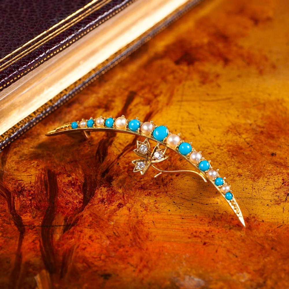 A Victorian 15ct yellow gold crescent brooch set with alternating turquoise cabochons and split pearls, featuring an offset diamond trefoil motif. View XIV