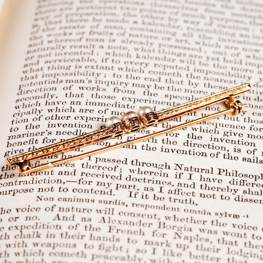An antique 18ct gold and platinum bar brooch featuring three central pearls flanked by a row of small diamonds. View V
