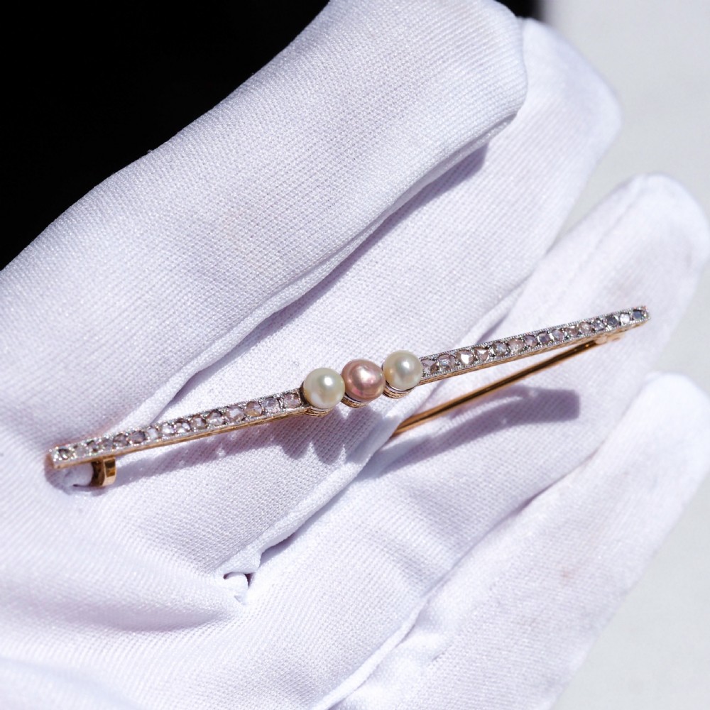 An antique 18ct gold and platinum bar brooch featuring three central pearls flanked by a row of small diamonds. View VIII