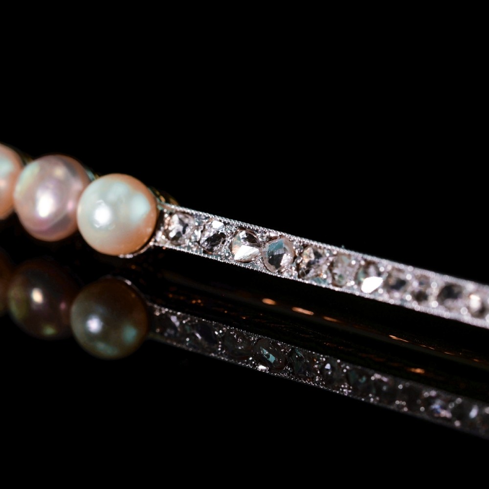 An antique 18ct gold and platinum bar brooch featuring three central pearls flanked by a row of small diamonds. View X