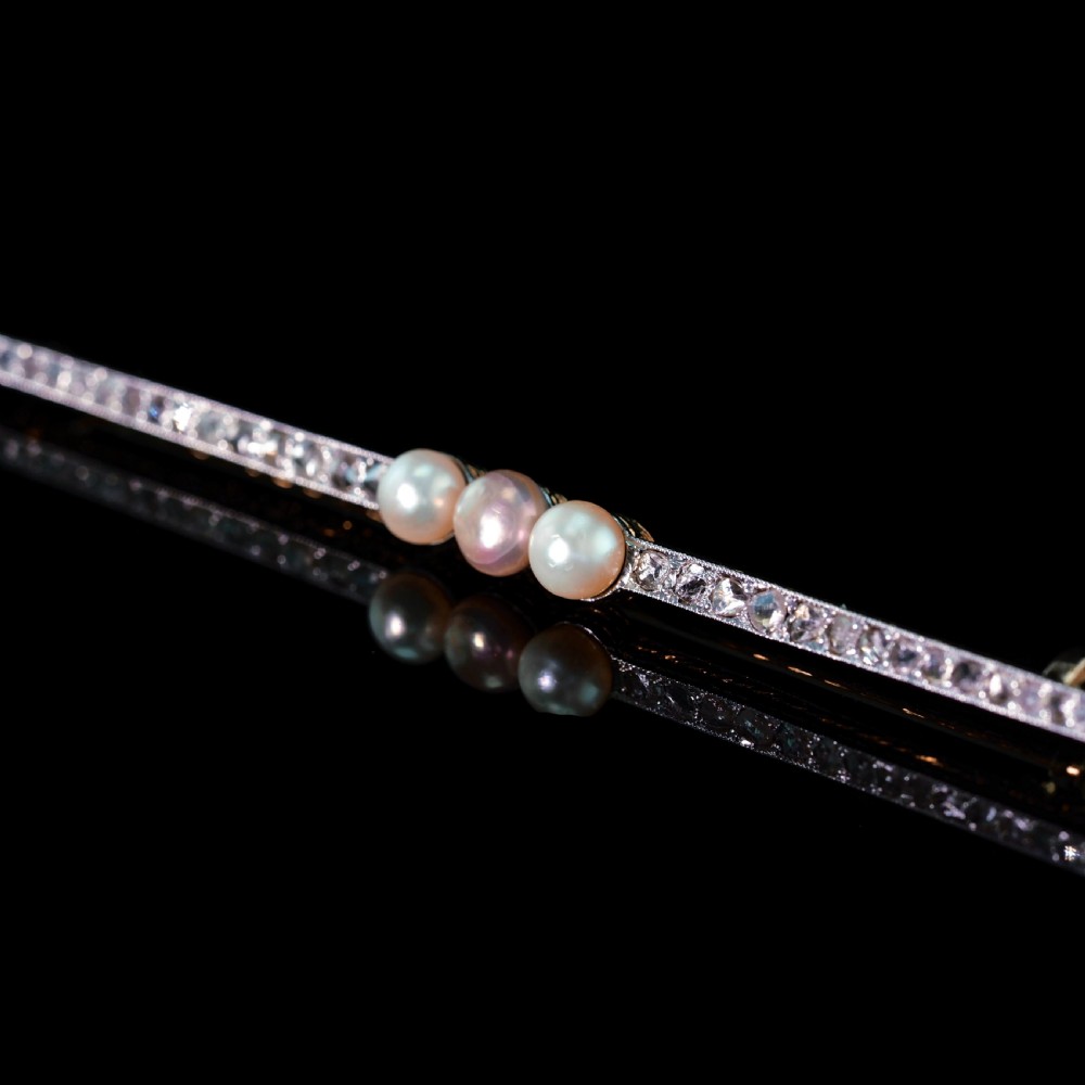 An antique 18ct gold and platinum bar brooch featuring three central pearls flanked by a row of small diamonds. View XI
