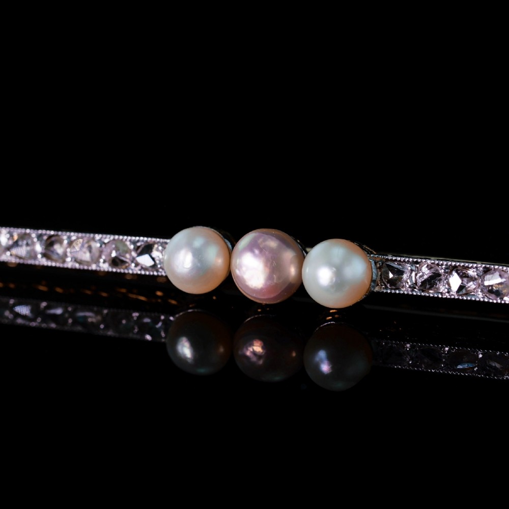 An antique 18ct gold and platinum bar brooch featuring three central pearls flanked by a row of small diamonds. View XII