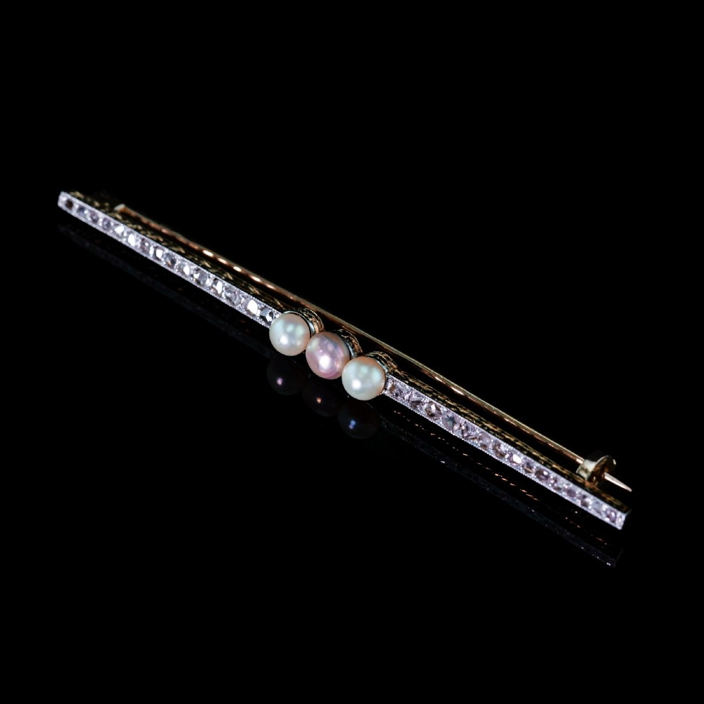 An antique 18ct gold and platinum bar brooch featuring three central pearls flanked by a row of small diamonds. View XIV