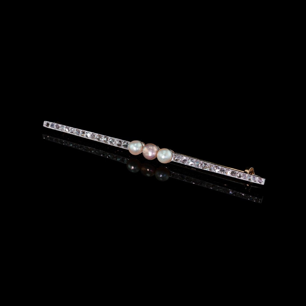 An antique 18ct gold and platinum bar brooch featuring three central pearls flanked by a row of small diamonds. View XV