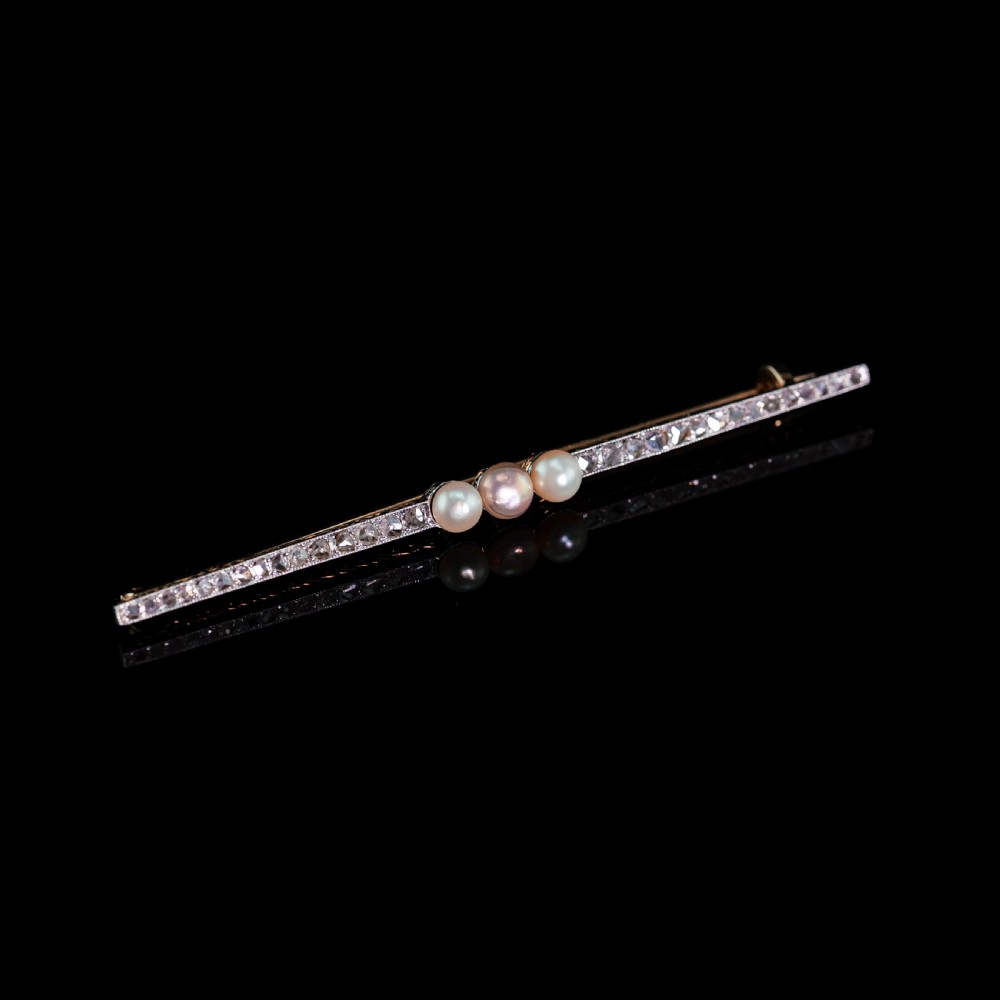 An antique 18ct gold and platinum bar brooch featuring three central pearls flanked by a row of small diamonds. View XVI