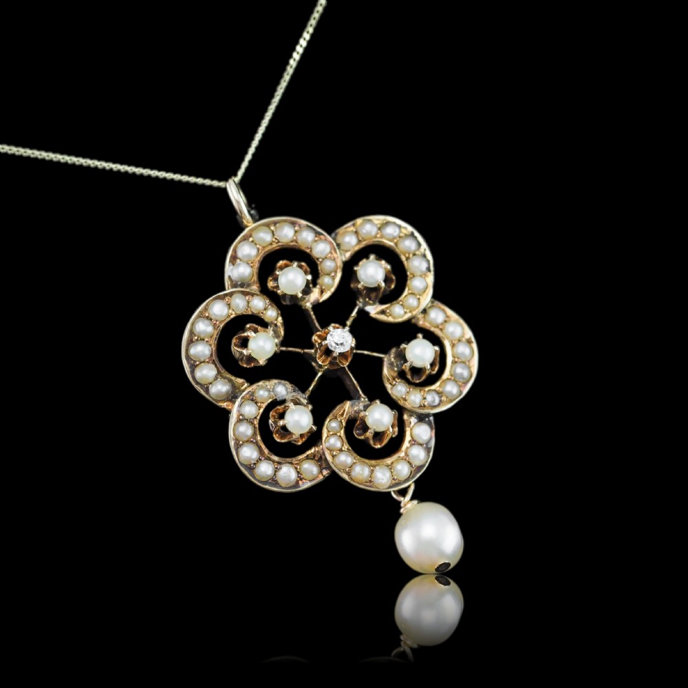 A Victorian 14ct yellow gold circular scrollwork pendant set with seed pearls, a central diamond, and an articulated pearl drop suspended from a fine chain. View II