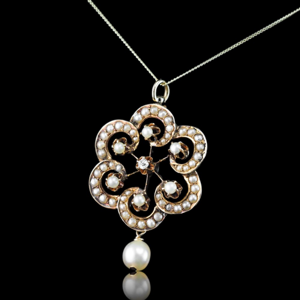 A Victorian 14ct yellow gold circular scrollwork pendant set with seed pearls, a central diamond, and an articulated pearl drop suspended from a fine chain. View IV