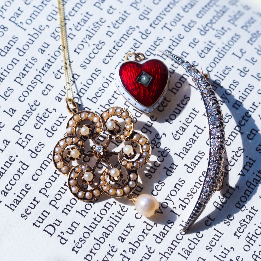 A Victorian 14ct yellow gold circular scrollwork pendant set with seed pearls, a central diamond, and an articulated pearl drop suspended from a fine chain. View XVI
