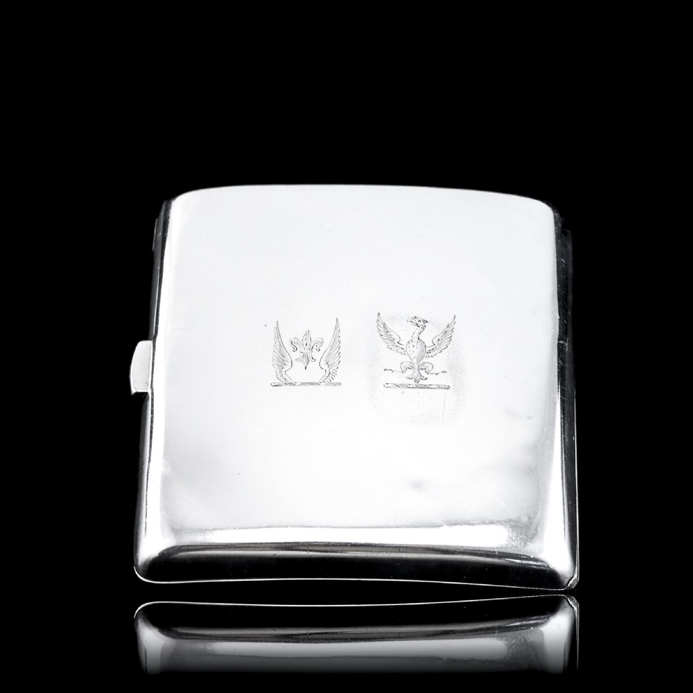 A polished Victorian sterling silver cigarette case featuring an engraved heraldic crest and curved profile resting on an open book. View XXI