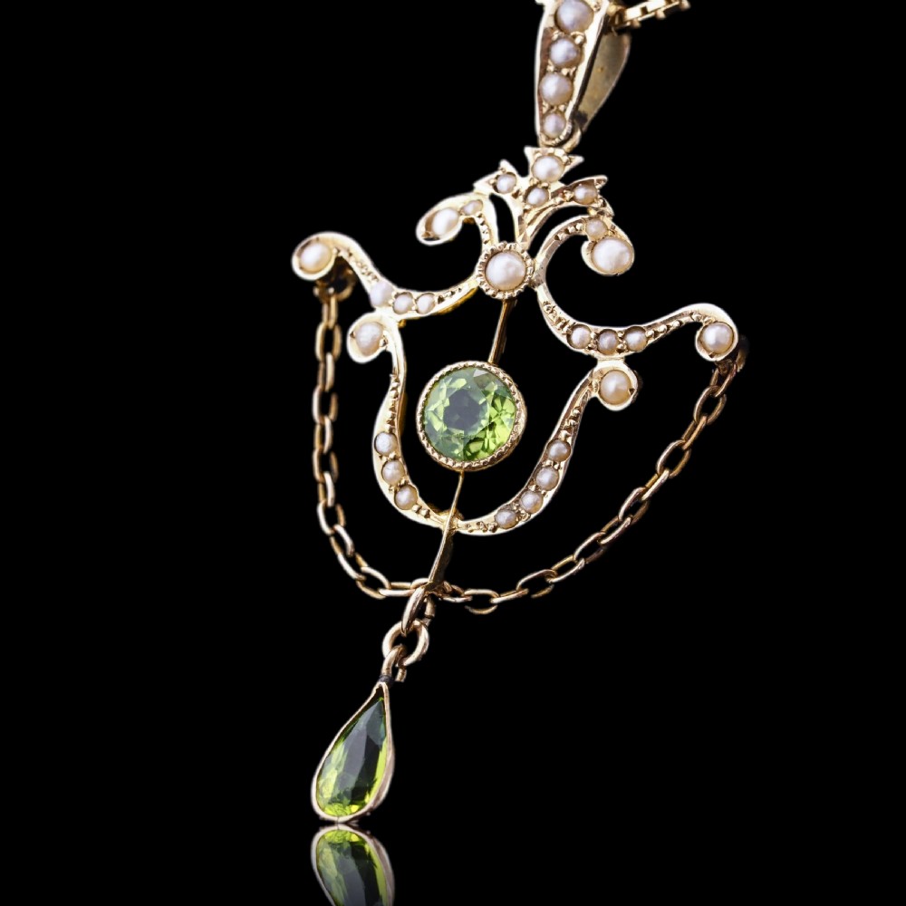 An Edwardian 9ct gold openwork pendant set with seed pearls, a central round peridot, and a dangling teardrop peridot. View IV