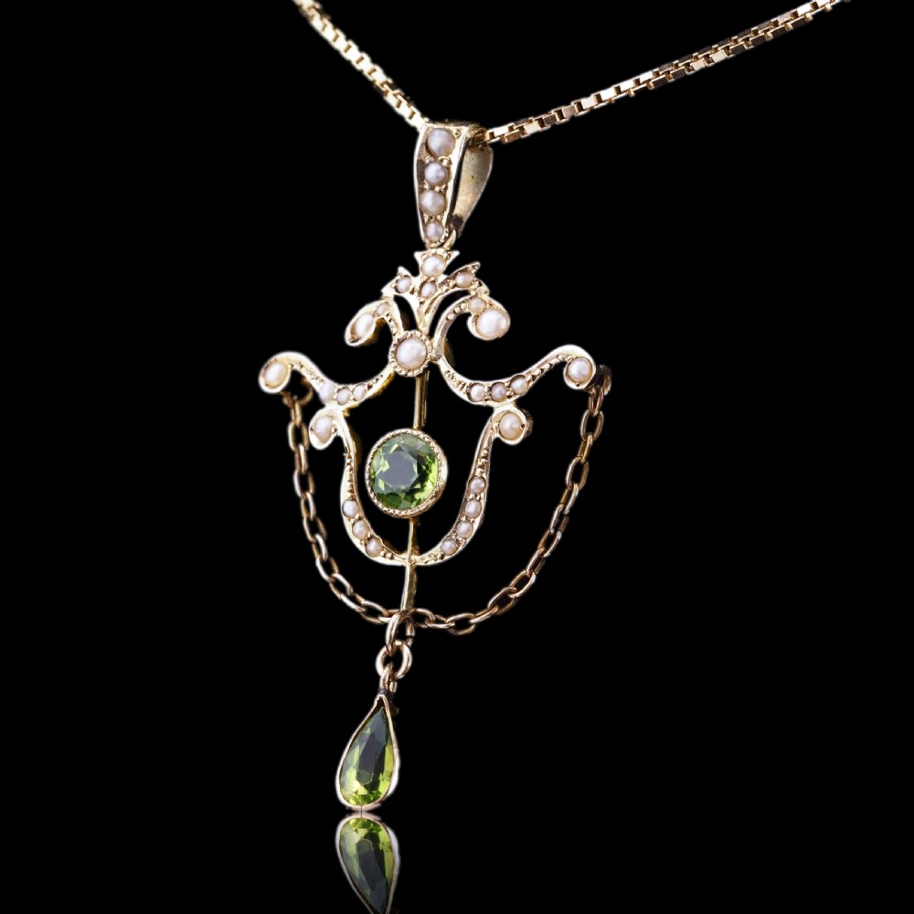 An Edwardian 9ct gold openwork pendant set with seed pearls, a central round peridot, and a dangling teardrop peridot. View V