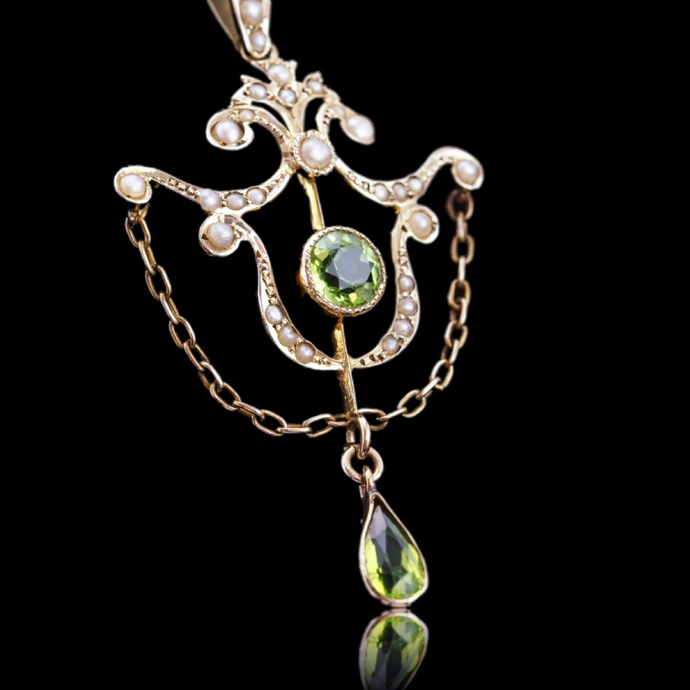 An Edwardian 9ct gold openwork pendant set with seed pearls, a central round peridot, and a dangling teardrop peridot. View VI