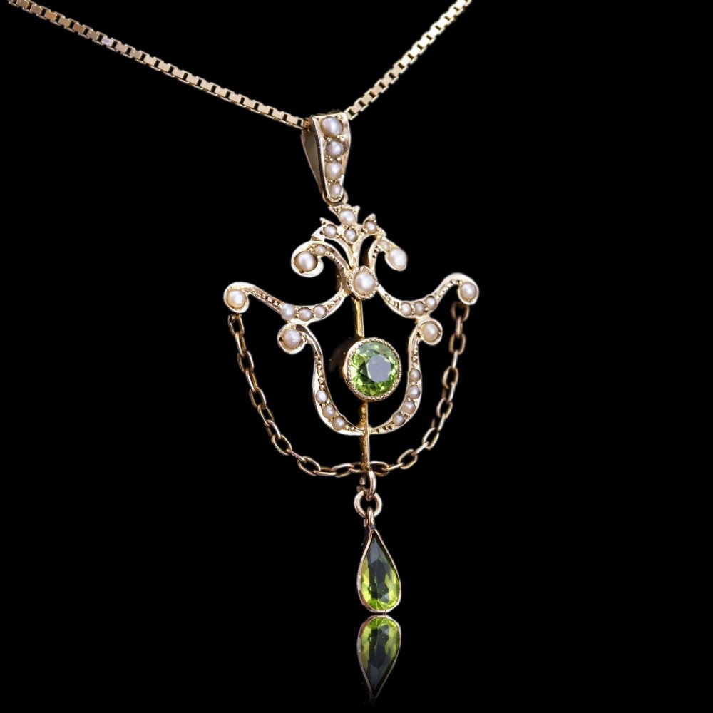 An Edwardian 9ct gold openwork pendant set with seed pearls, a central round peridot, and a dangling teardrop peridot. View VII