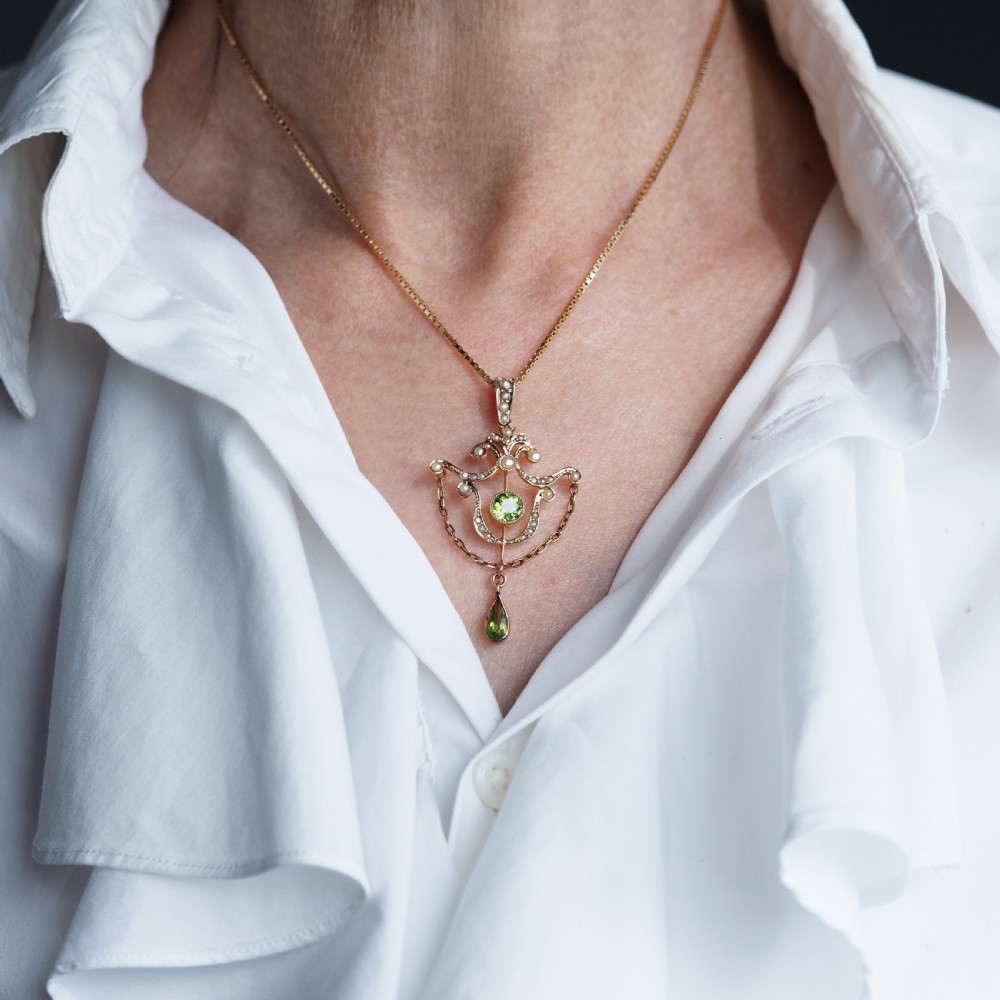 An Edwardian 9ct gold openwork pendant set with seed pearls, a central round peridot, and a dangling teardrop peridot. View VIII