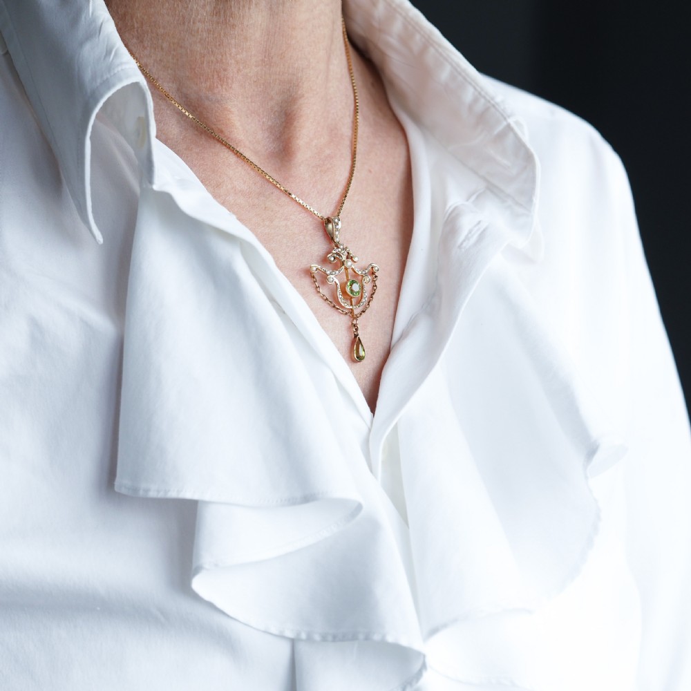 An Edwardian 9ct gold openwork pendant set with seed pearls, a central round peridot, and a dangling teardrop peridot. View IX