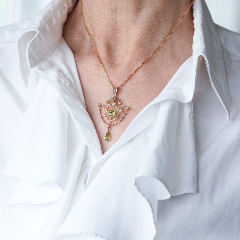An Edwardian 9ct gold openwork pendant set with seed pearls, a central round peridot, and a dangling teardrop peridot. View XI