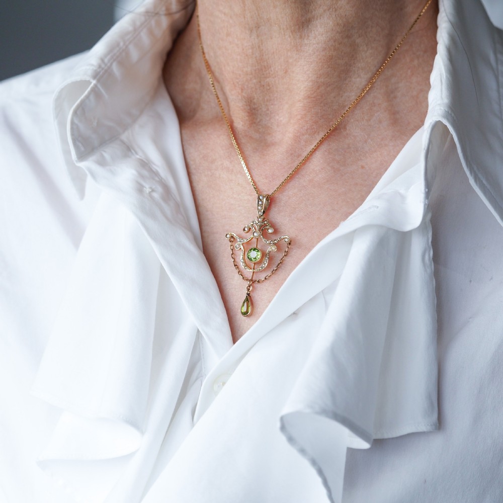 An Edwardian 9ct gold openwork pendant set with seed pearls, a central round peridot, and a dangling teardrop peridot. View XII