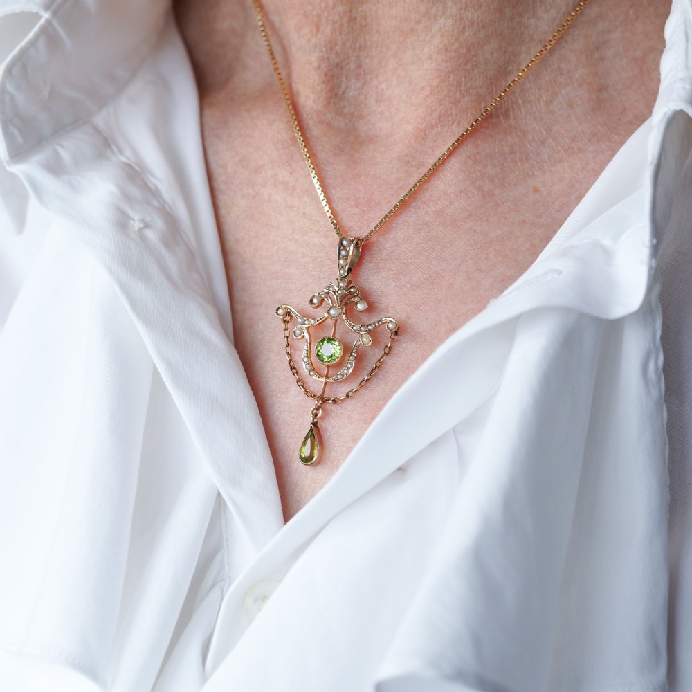 An Edwardian 9ct gold openwork pendant set with seed pearls, a central round peridot, and a dangling teardrop peridot. View XIII