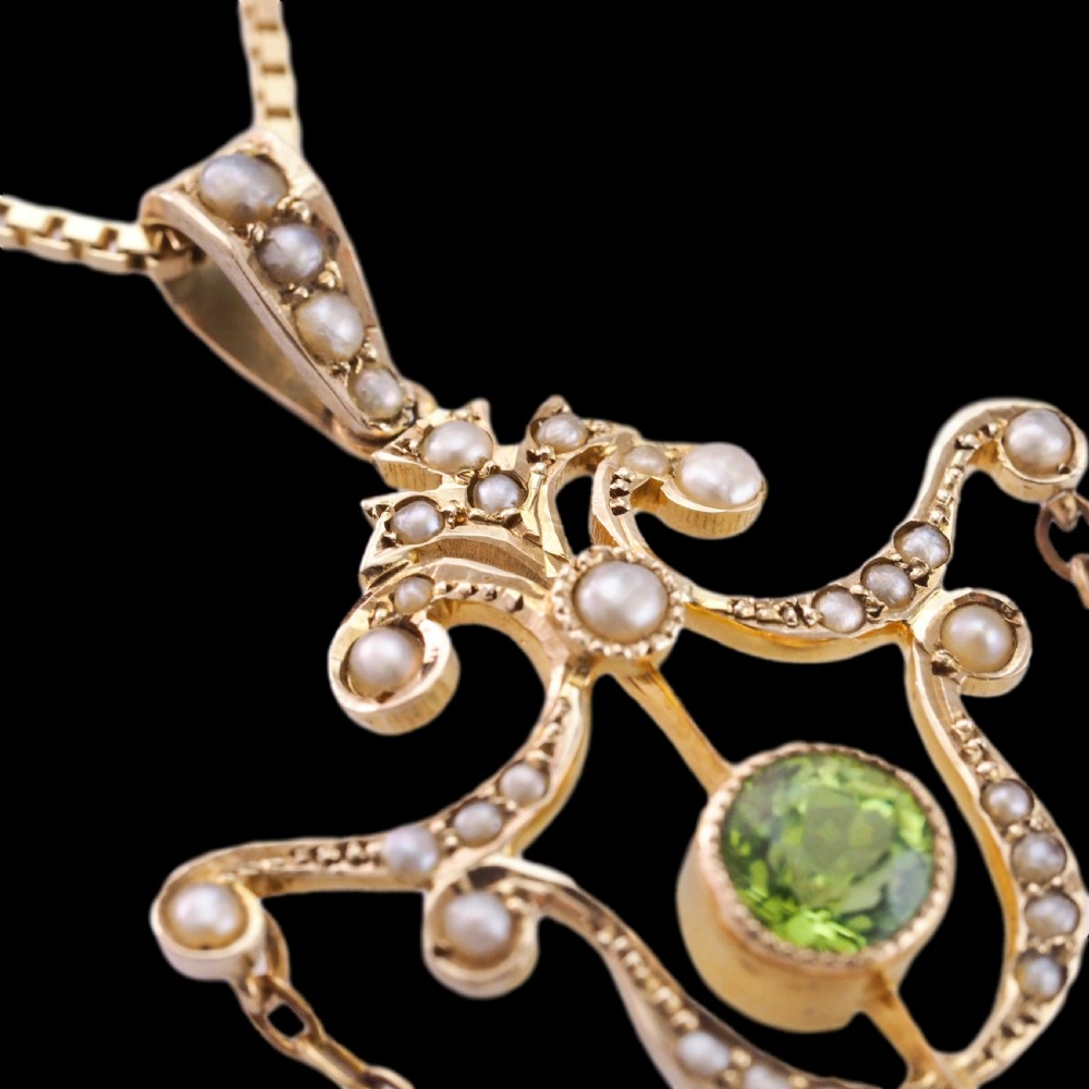 An Edwardian 9ct gold openwork pendant set with seed pearls, a central round peridot, and a dangling teardrop peridot. View XIV