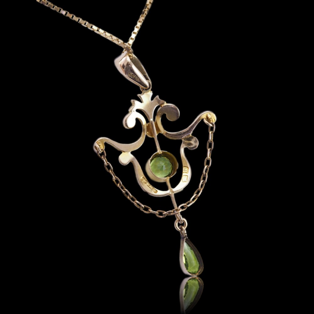 An Edwardian 9ct gold openwork pendant set with seed pearls, a central round peridot, and a dangling teardrop peridot. View XVI