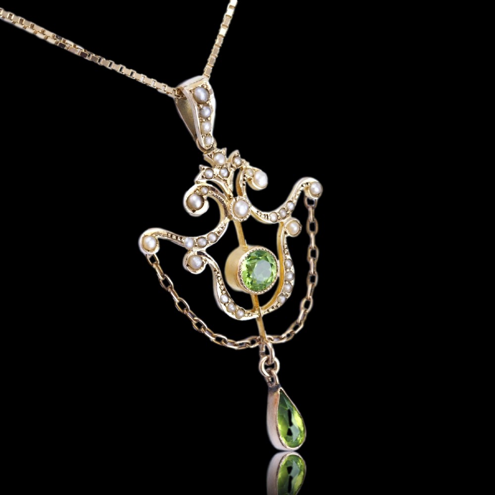 An Edwardian 9ct gold openwork pendant set with seed pearls, a central round peridot, and a dangling teardrop peridot. View XVII