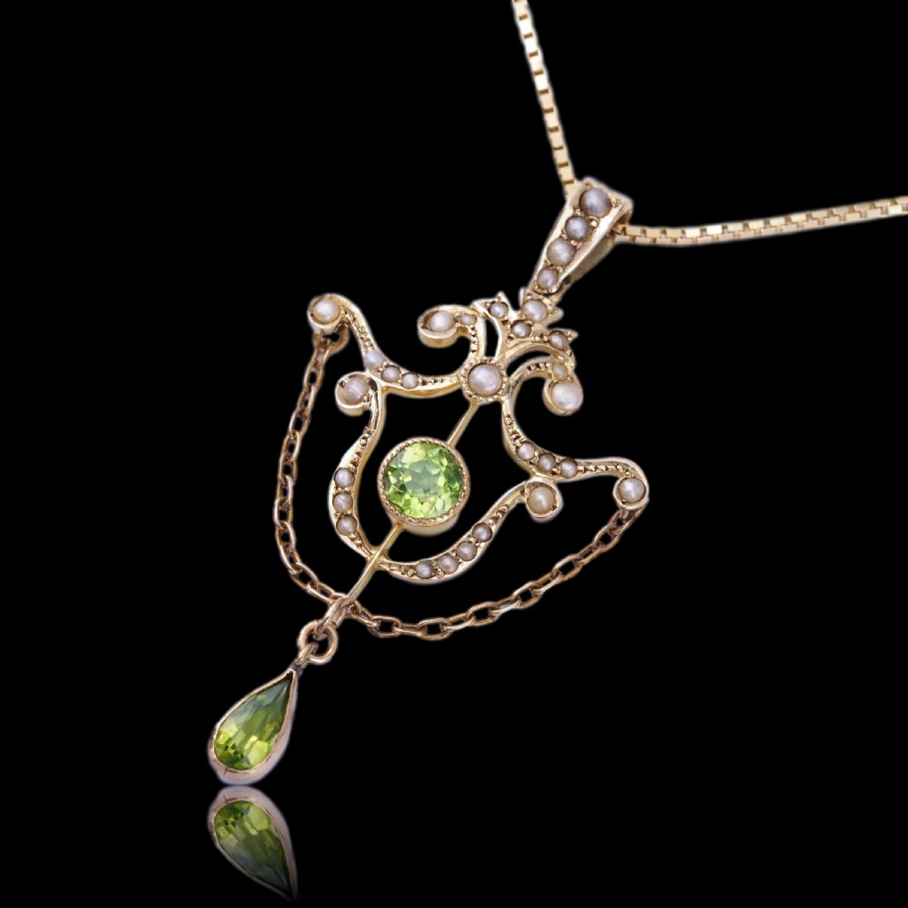 An Edwardian 9ct gold openwork pendant set with seed pearls, a central round peridot, and a dangling teardrop peridot. View XVIII