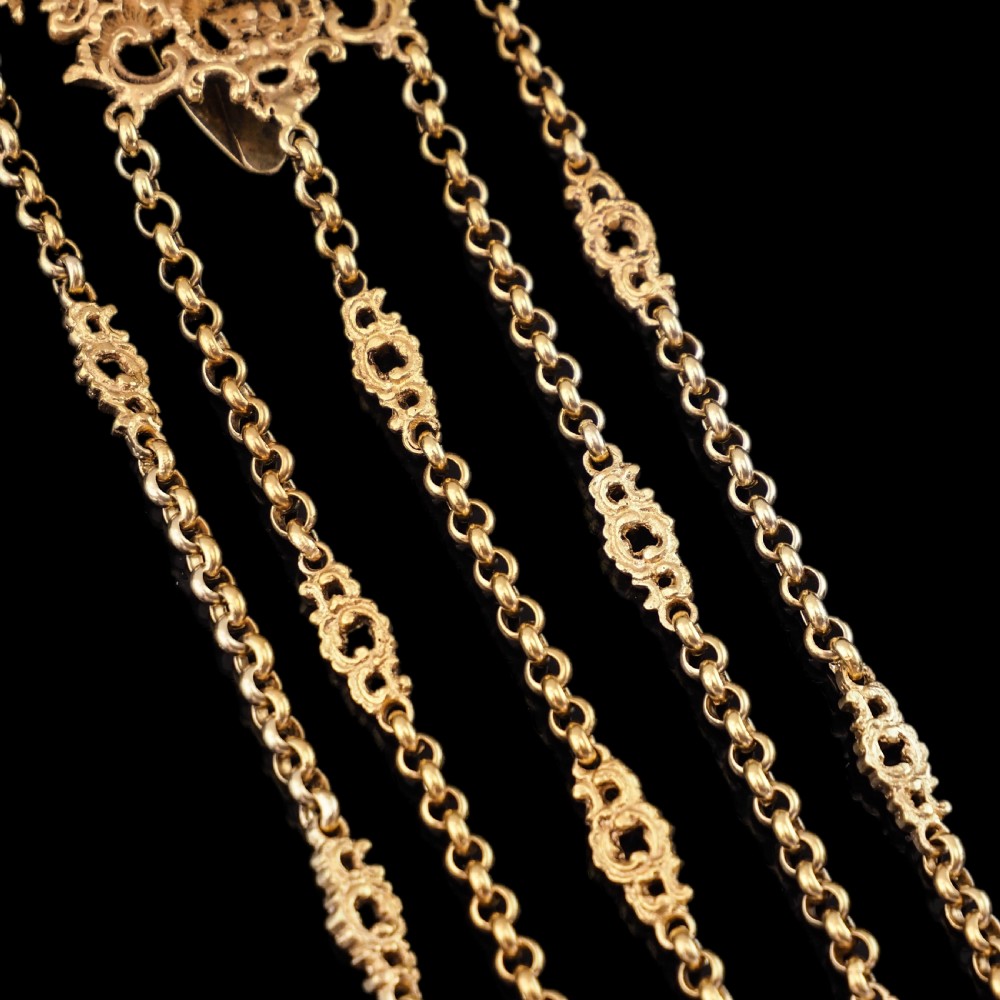An ornate Victorian silver-gilt chatelaine featuring five hanging chains with swivel clips and a rococo plaque detailed with a central cherub motif. View II