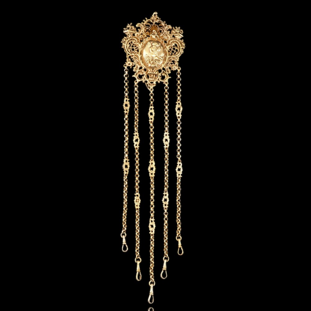 An ornate Victorian silver-gilt chatelaine featuring five hanging chains with swivel clips and a rococo plaque detailed with a central cherub motif. View IV