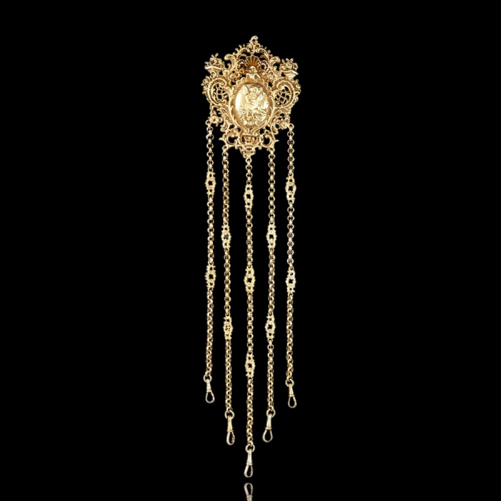 An ornate Victorian silver-gilt chatelaine featuring five hanging chains with swivel clips and a rococo plaque detailed with a central cherub motif. View V