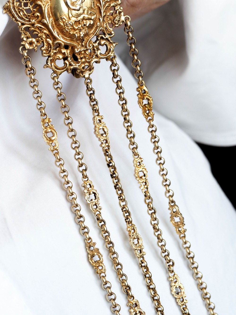 An ornate Victorian silver-gilt chatelaine featuring five hanging chains with swivel clips and a rococo plaque detailed with a central cherub motif. View VII