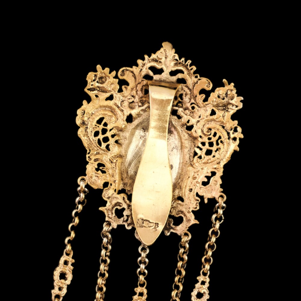 An ornate Victorian silver-gilt chatelaine featuring five hanging chains with swivel clips and a rococo plaque detailed with a central cherub motif. View XVIII