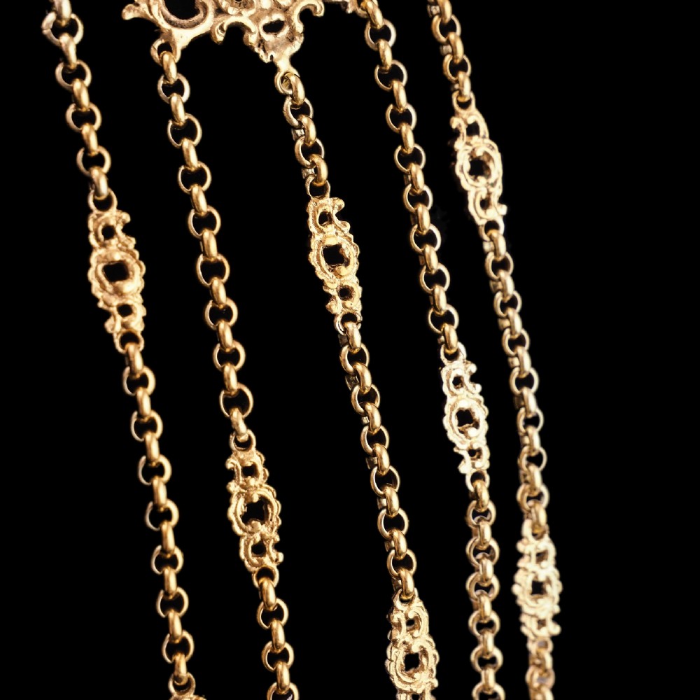An ornate Victorian silver-gilt chatelaine featuring five hanging chains with swivel clips and a rococo plaque detailed with a central cherub motif. View XXI