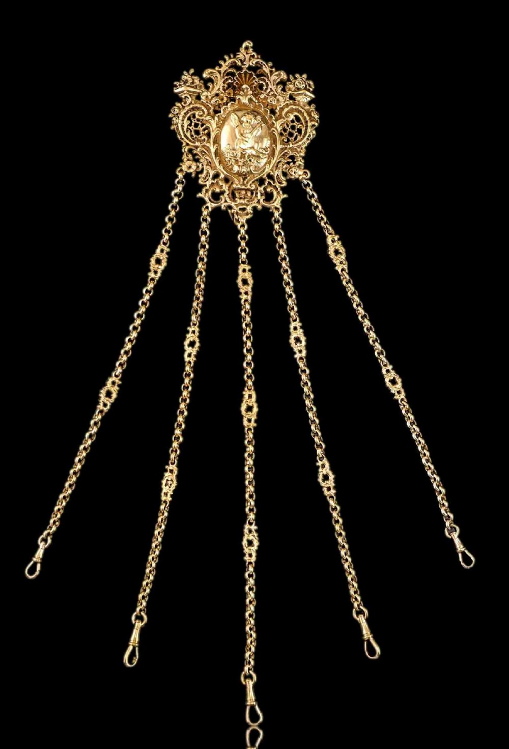 An ornate Victorian silver-gilt chatelaine featuring five hanging chains with swivel clips and a rococo plaque detailed with a central cherub motif.