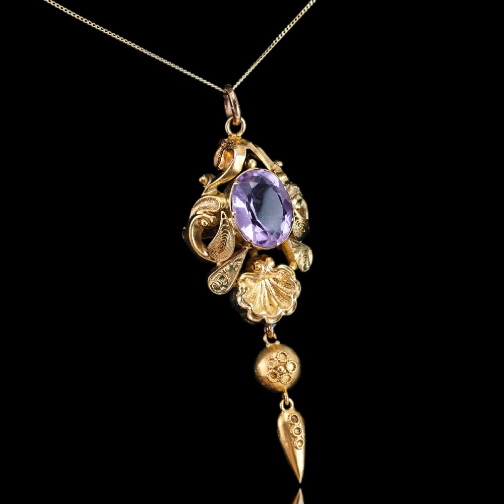 An antique 14ct yellow gold Victorian pendant featuring a central oval faceted amethyst surrounded by scrollwork, a shell motif, and an articulated drop element. View II