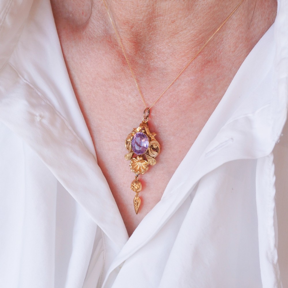 An antique 14ct yellow gold Victorian pendant featuring a central oval faceted amethyst surrounded by scrollwork, a shell motif, and an articulated drop element. View III