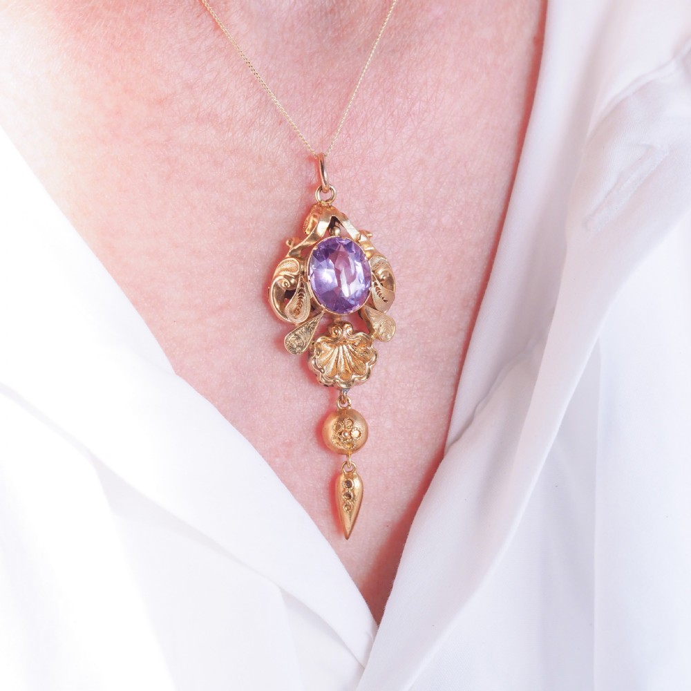 An antique 14ct yellow gold Victorian pendant featuring a central oval faceted amethyst surrounded by scrollwork, a shell motif, and an articulated drop element. View IV