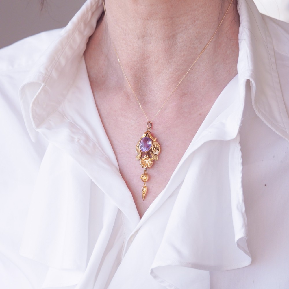 An antique 14ct yellow gold Victorian pendant featuring a central oval faceted amethyst surrounded by scrollwork, a shell motif, and an articulated drop element. View VII